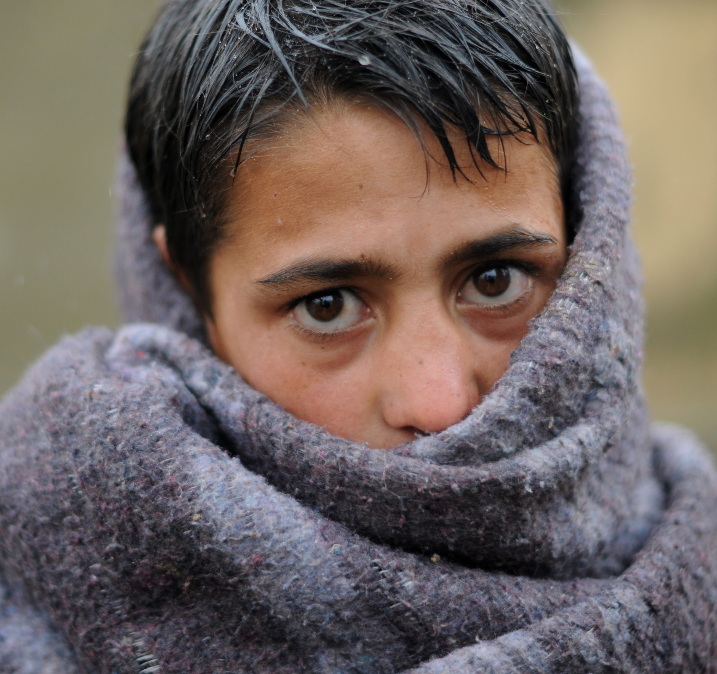 Teenage refugee boy wrapped in a blanket