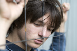 Teenage boy up against wire fence